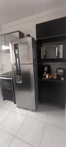 een keuken met een roestvrijstalen koelkast en zwarte kasten bij Refúgio Premium UTFPR in Londrina