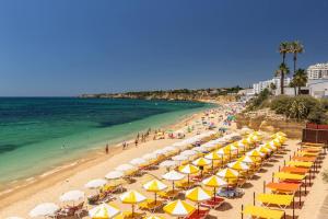 einen Strand mit gelben und weißen Sonnenschirmen und dem Meer in der Unterkunft Luxury Beach Apartment at Armação de Pêra in Armação de Pêra