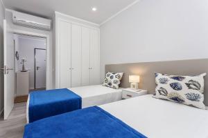 ein Schlafzimmer mit zwei Betten mit blauen und weißen Kissen in der Unterkunft Luxury Beach Apartment at Armação de Pêra in Armação de Pêra