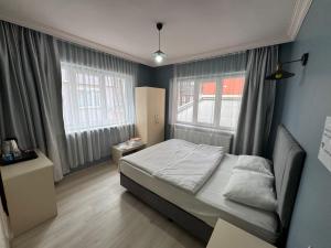 a small bedroom with a bed and two windows at Flora Otel 16 rooms in Edirne