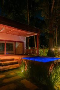a backyard with a house with a blue pool at night at casa refugio das bromelhas in Itacaré