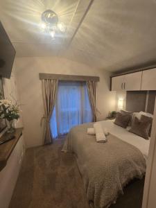 a bedroom with a large bed and a window at Chillingham lodge with hot tub Felmoor Park in Felton