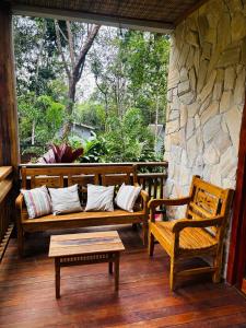 a porch with two benches and a stone wall at casa refugio das bromelhas in Itacaré