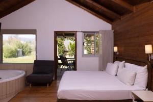 Nofey HaBashan Country Lodging في Lahavot HaBashan: غرفة نوم بسرير وحوض استحمام وكرسي