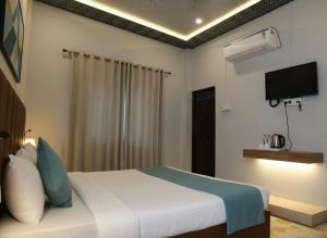 バラナシにあるHotel Valencia Innのベッドと薄型テレビのある寝室