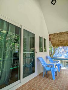 two blue chairs sitting on a porch with windows at Baan Suan Kayoo 2 Buffalo Bay Aow Khao Kwai in Ko Phayam