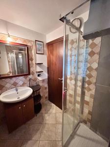 B&B Ginepro blu في بورتوسكوسو: حمام مع حوض ودش زجاجي