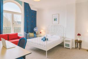 a bedroom with a white bed and a red couch at Flora's Palace - The Hague Scheveningen in The Hague
