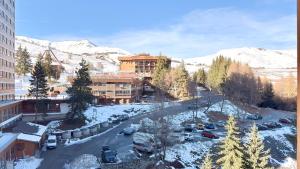 T3 Vanguard in front of ski school في Villarembert: اطلالة على مدينة فيها جبال مغطاة بالثلج