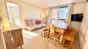 T3 Vanguard in front of ski school في Villarembert: غرفة معيشة مع طاولة وأريكة