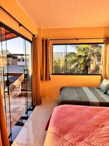 um quarto com duas camas e uma janela grande em Refúgio Colonial - Figueira - Praia de Mauá em Majé