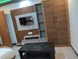 a living room with a tv and a coffee table at Hotel 7R RESIDENCY in Jhānsi