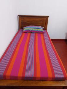 una cama con un colorido edredón a rayas en ella en Villa Aavanthana, en Ambalangoda