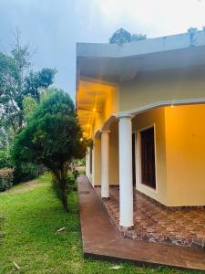 a yellow building with columns and a grass yard at DropHaus in Naula +3 photos