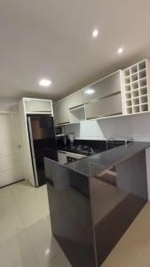 a kitchen with a black counter top and white cabinets at Resort Flat Gavoa in Igarassu
