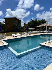 a large swimming pool with chairs and a building at Resort Flat Gavoa in Igarassu