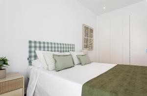 Un dormitorio con una cama blanca con almohadas verdes y blancas en Design Apartment Disneyland Paris, en Chessy