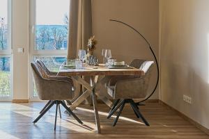 Abbey View Suites في Echternacherbrück: طاولة غرفة الطعام مع الكراسي وكؤوس النبيذ