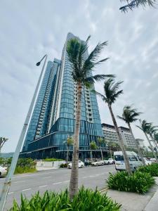 a tall building with palm trees in front of it at A LA CARTE Hạ Long Bay View biển tầng cao in Ha Long
