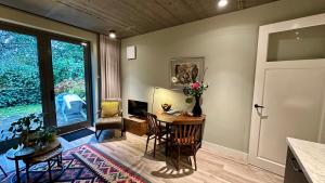 a living room with a desk and a table with flowers on it at Luxe B&B "In de Schulp", ontspan en geniet van comfort en stijl in Amstelveen
