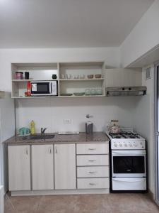 eine Küche mit weißen Schränken und einem Herd mit Backofen in der Unterkunft Rincón del cielo in Mar del Plata