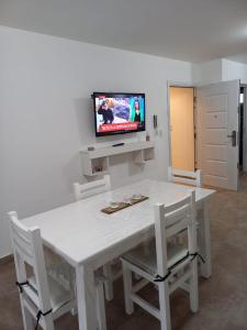 einen weißen Tisch mit Stühlen und einen TV an der Wand in der Unterkunft Rincón del cielo in Mar del Plata