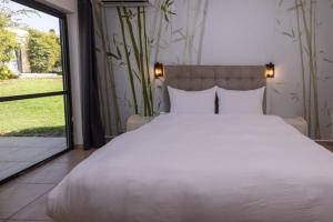 Un dormitorio con una cama blanca grande y una ventana en Nofey HaBashan Country Lodging, en Lahavot HaBashan