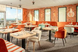 a restaurant with tables and chairs and windows at Hôtel de la Baie - Thalassothérapie PREVITHAL in Donville-les-Bains