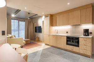 a kitchen with wooden cabinets and a living room at Break Sokos Hotel Himos in Jämsä
