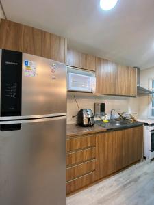 Apartamento vista mar, 2 quartos, bairro Fazenda, Itajai, SC في إيتاجاي: مطبخ مع ثلاجة من الفولاذ المقاوم للصدأ وخزائن خشبية