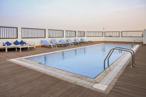 a large swimming pool with blue chairs in a building at Sherao Hotel Doha - Next to National Museum of Qatar & Metro - فندق شراعوة الدوحة - بجانب متحف قطر الوطني ومحطة المترو in Doha