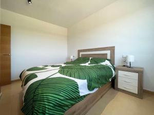 een slaapkamer met een groen-wit bed en een nachtkastje bij Las Terrazas Golf Cédric in Torre-Pacheco