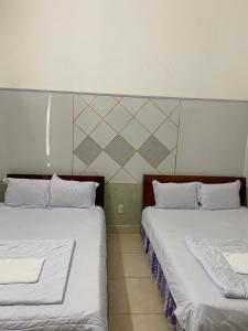 Khách sạn Thiên Nga في Gia Nghĩa: سريرين يجلسان بجانب بعضهما البعض في غرفة +صورتان