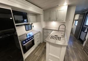 a small kitchen with white cabinets and a sink at Luxury Oceanfront Trailer Home Cerritos in San Carlos +4 photos