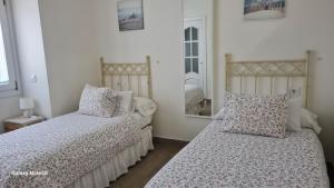 een slaapkamer met twee bedden en een spiegel bij Casita de María in El Puerto de Santa María