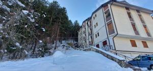 Rifugio dei Pini في روكاراسو: مبنى في الثلج مع سيارة متوقفة بجواره