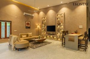 a living room with a couch and a tv at EKOSTAY - The Clay House in Alibaug