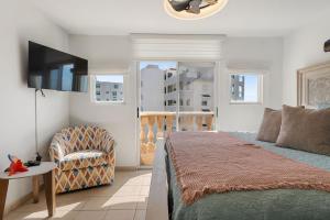 a bedroom with a bed and a chair and a television at Costa Ensenada Penthouse 505 across the street from Balneario beach in Rincon +22 photos