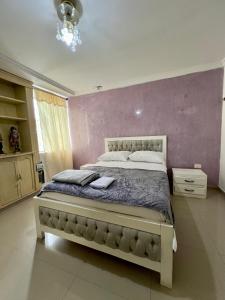 a bedroom with a large bed with a purple wall at Casa full Confort en el corazón de valledupar in Valledupar