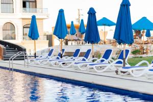 a row of chairs and umbrellas next to a pool at فندق لوريت in Qaryat at Ta‘mīr as Siyāḩīyah +8 photos