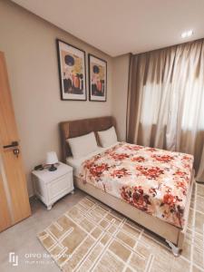 Un dormitorio con una cama con una colcha floral. en فندق لوريت, en Qaryat at Ta‘mīr as Siyāḩīyah