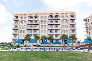 a large building with blue umbrellas in front of it at فندق لوريت in Qaryat at Ta‘mīr as Siyāḩīyah