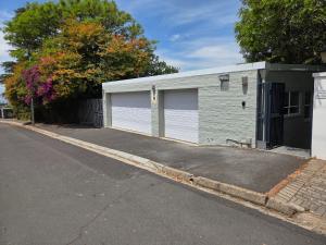 a building with two garage doors next to a street at SleepINN at Dumont in Paarl