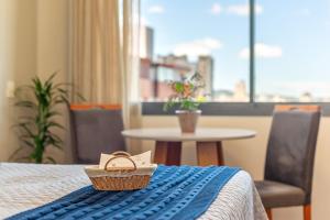 a basket on a bed in a room with a table at Skyline Moinhos de Vento in Porto Alegre