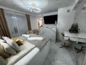 a white bedroom with a bed and a television at GOLD apartment in Święta Katarzyna