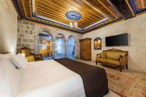 a bedroom with a bed and a flat screen tv at Cappadocia Secret Hill Cave Suites in Goreme