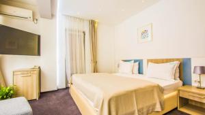 Una habitación de hotel con una cama grande y un televisor. en Parliament Square, en Bucarest