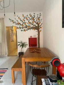 a dining room table with a tree painted on the wall at Casa Laranja Hostel in Niterói +2 photos
