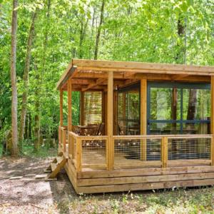 a wooden building with a chicken cage in the woods at La Clairière - Écocamping en vallée de la Dordogne in Lamothe-Fénelon