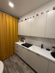 a kitchen with white cabinets and a yellow curtain at Apartament for Guest in Jelgava